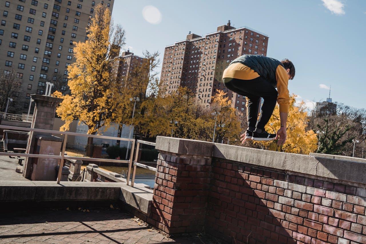Unrecognizable male in activewear performing stunt while practicing parkour on street of city