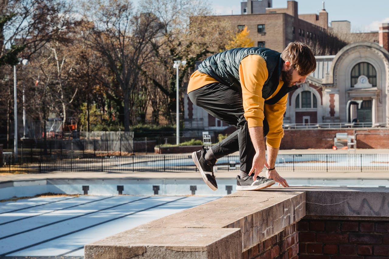 Side view of focused male athlete in activewear preparing for stunt on brick building